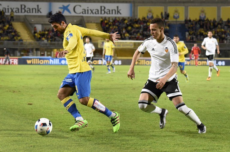 Rodrigo (I) del Valencia va por la pelota ante Culio hoy en Canarias. Foto AFP