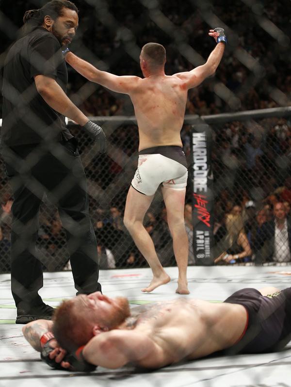 El árbitro Herb Dean detiene la pelea entre Nate Díaz y Conor McGregor en el suelo. (AP)