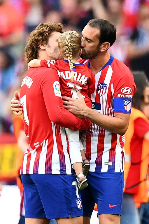 Diego Godín (D) besa a su ahijada, la hija del delantero francés Antoine Griezmann (I), en el partido despedida del futbolista uruguayo