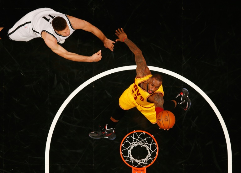 LeBron James, #23 de Cleveland Cavaliers, lanza marcado por Brook Lopez, #11 de Brooklyn Nets, en duelo de la liga NBA en el Barclays Center el 24 de marzo de 2016 en Nueva York. / AFP / AL BELLO