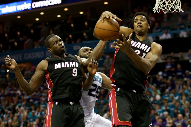 El británico de origen sudanés Luol Deng (9) y su compañero Hassan Whiteside (#21), de los Miami Heats, pelean por el balón contra Al Jefferson (#25), de los Charlotte Hornet, en el 4° juego de los cuartos de final en playoffs de la NBA, en Charlotte, el 25 de abril de 2016. / AFP / STREETER LECKA
