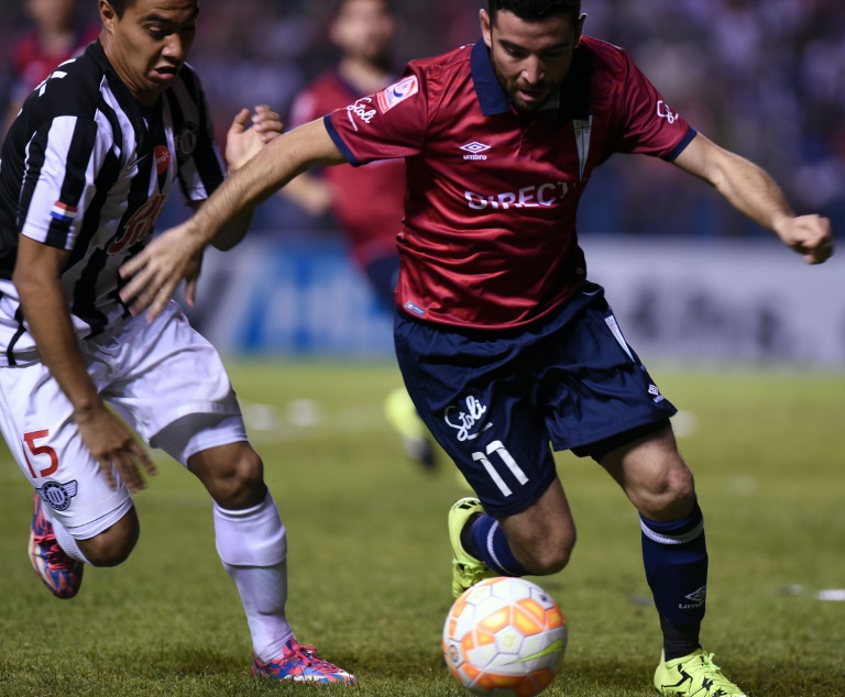 El jugador de la Universidad Católica de Chile, Fernando Cordero (D), compite por el balón con el volante del paraguayo Libertad, Ángel Lucena, durante partido de Copa Sudamericana en el estadio Nicolás Leoz, en Asunción, Paraguay, el 17 de setiembre de 2015. / AFP / NORBERTO DUARTE